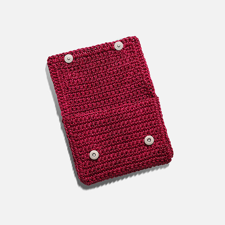 THE CLUTCH BAG in cherry red — side view showing the fold-over flap and hand-crocheted leather texture
