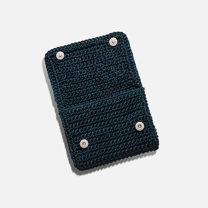 THE CLUTCH BAG in petrol — side view showing the fold-over flap and hand-crocheted leather texture