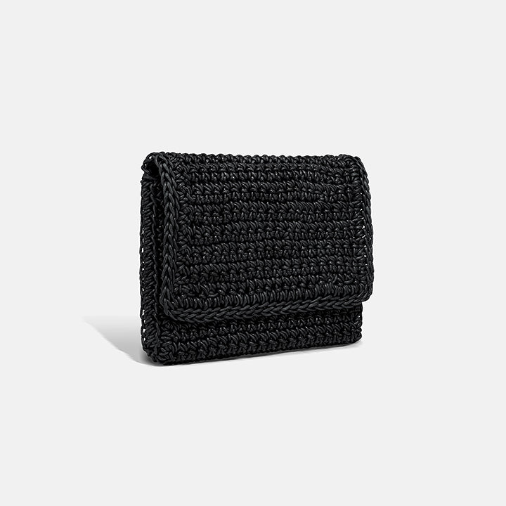 THE CLUTCH BAG in black — side view showing the fold-over flap and hand-crocheted leather texture
