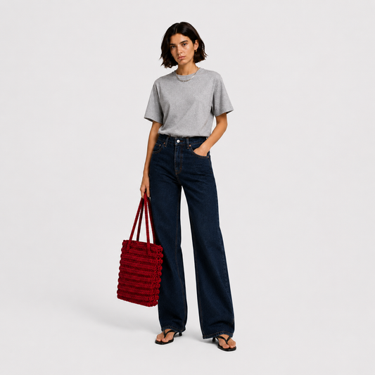 Model wearing THE STAPLE BAG in red as a daily shoulder tote, styled with grey tee and dark denim