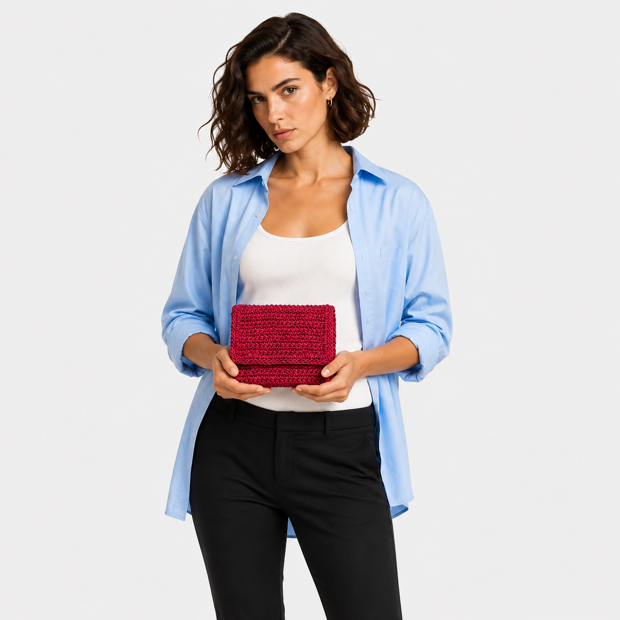 Close-up of model holding THE CLUTCH BAG in cherry red, hand-crocheted leather texture in detail