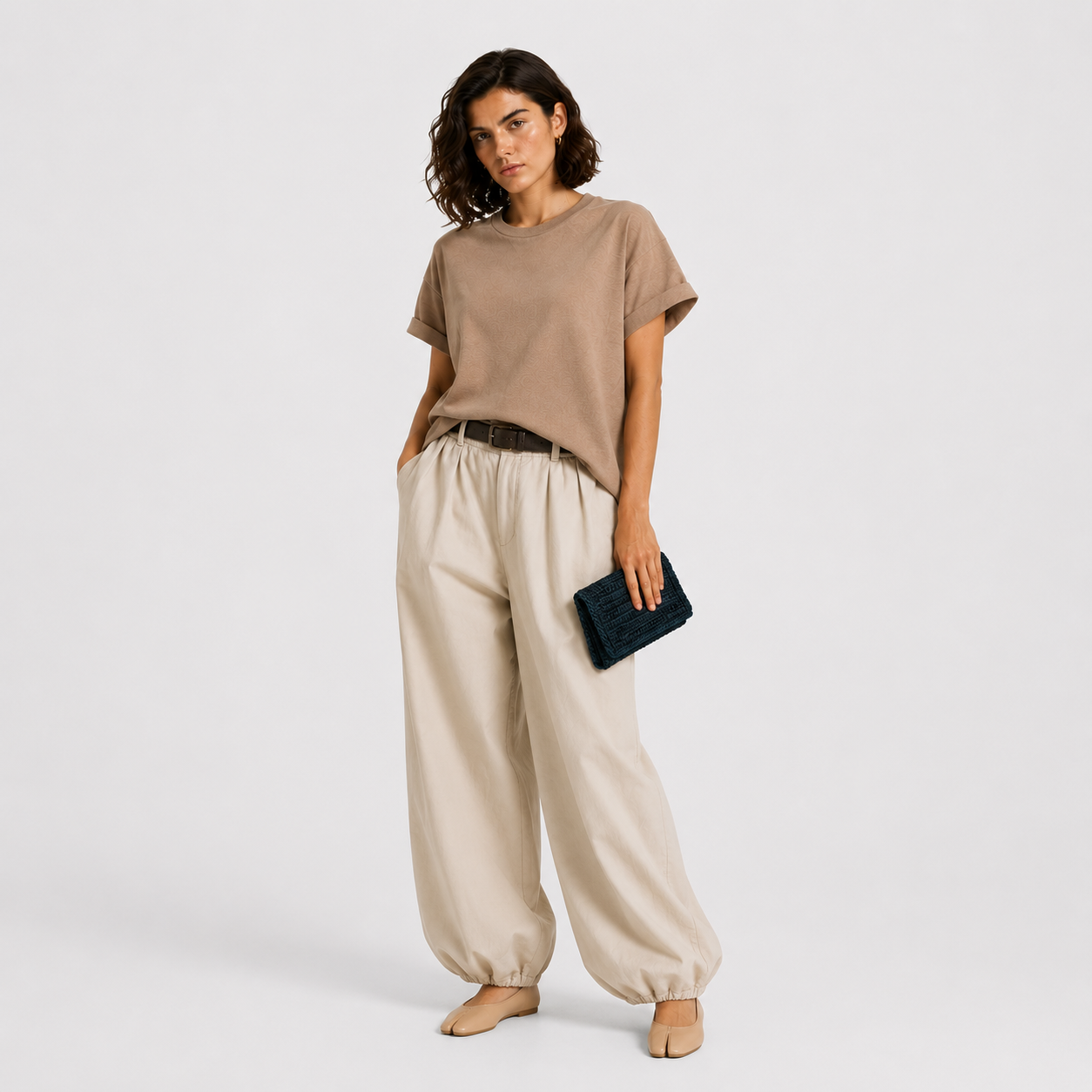 Model holding THE CLUTCH BAG in petrol, styled with mocha tee and cream wide-leg trousers | PROVE'M WRONG